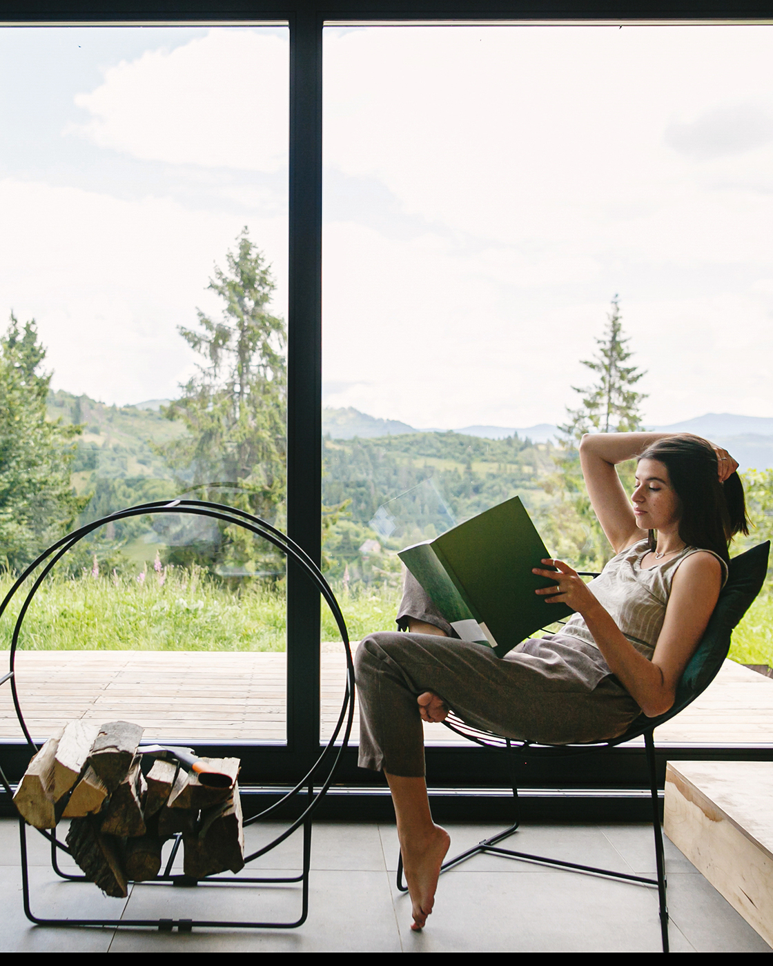 Beautiful stylish woman reading book, sitting on chair at firepl