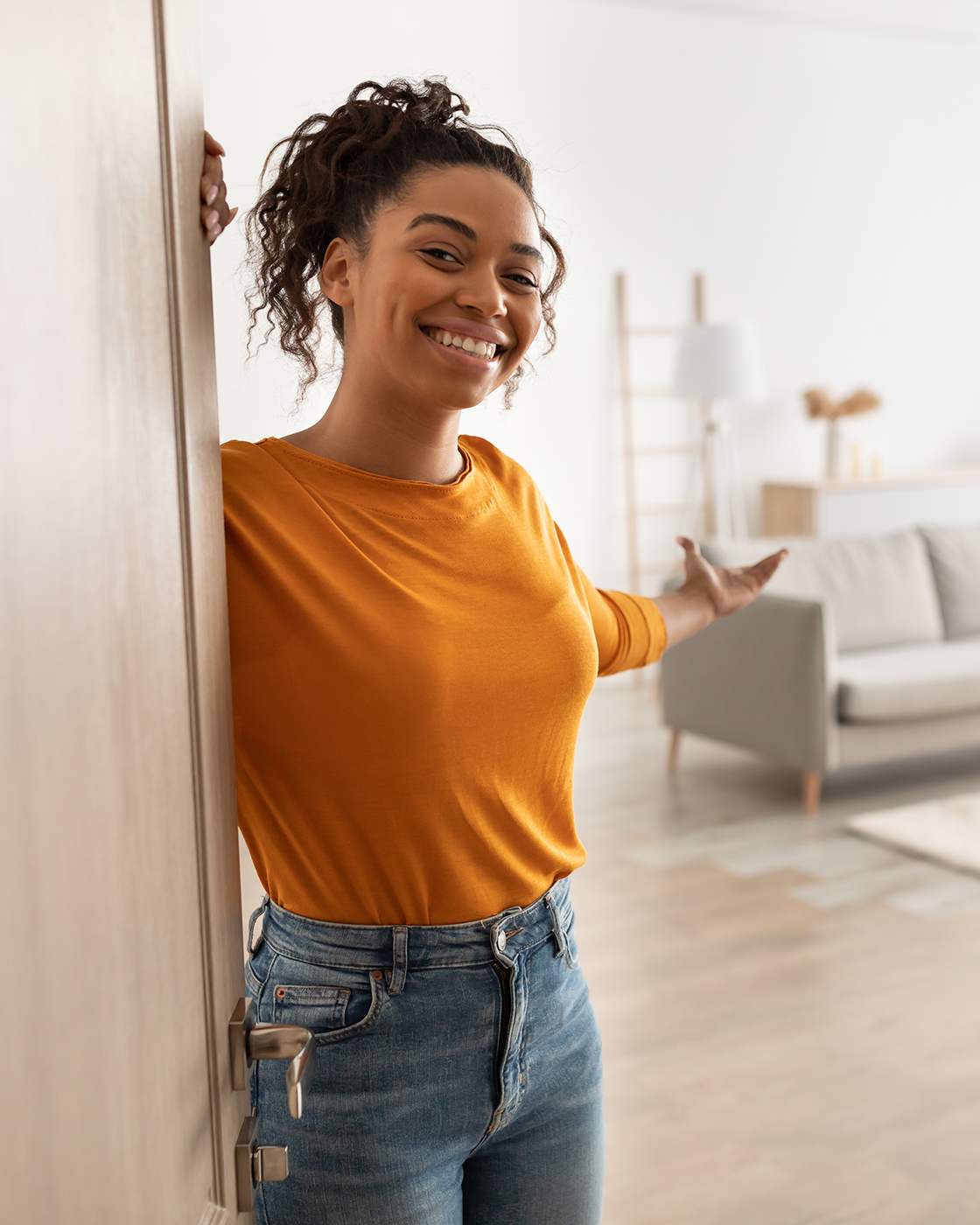Cheerful African Woman Opening Door Welcoming You Standing At Home