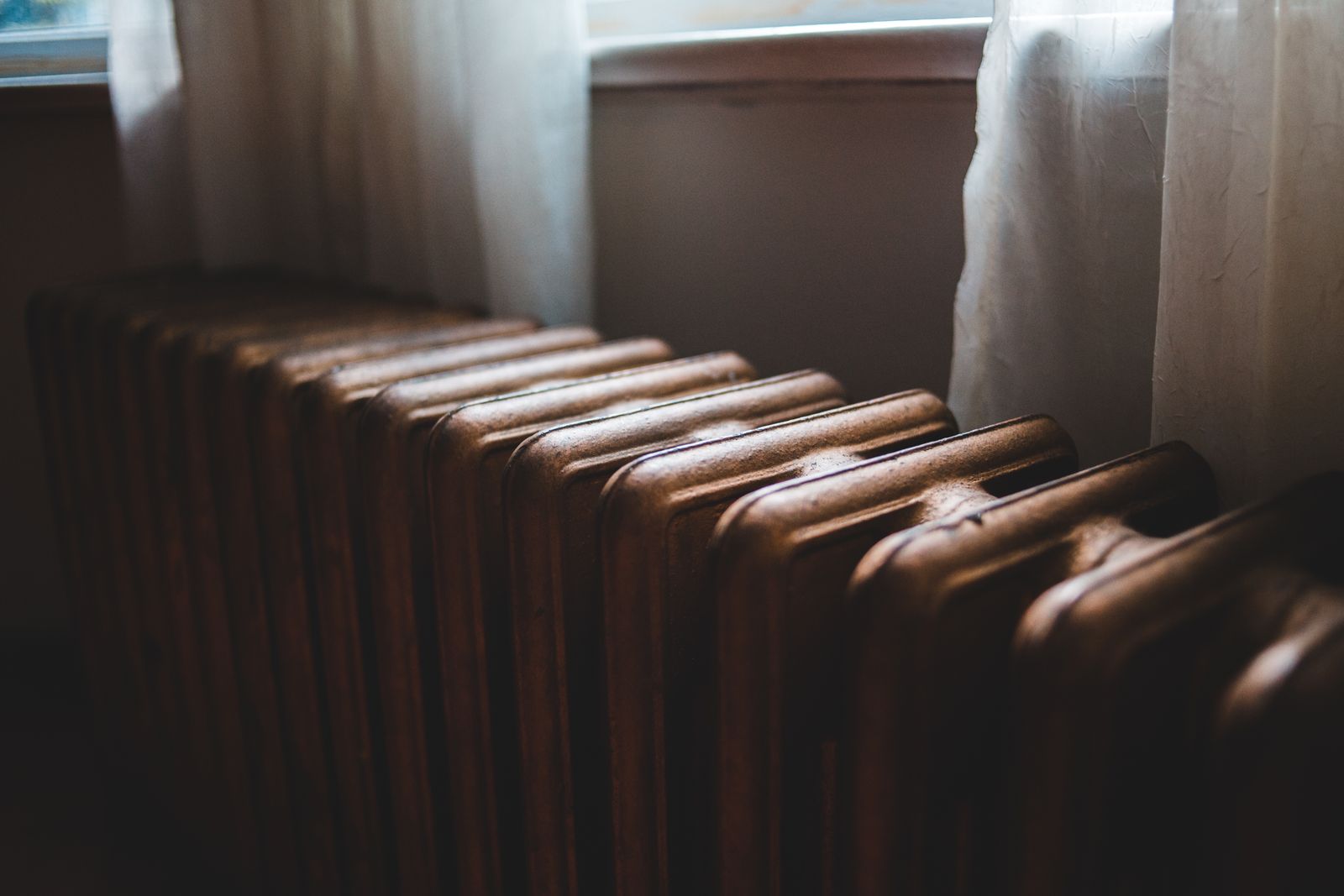 Vieux radiateur en fonte sous une fenêtre dans un logement ancien