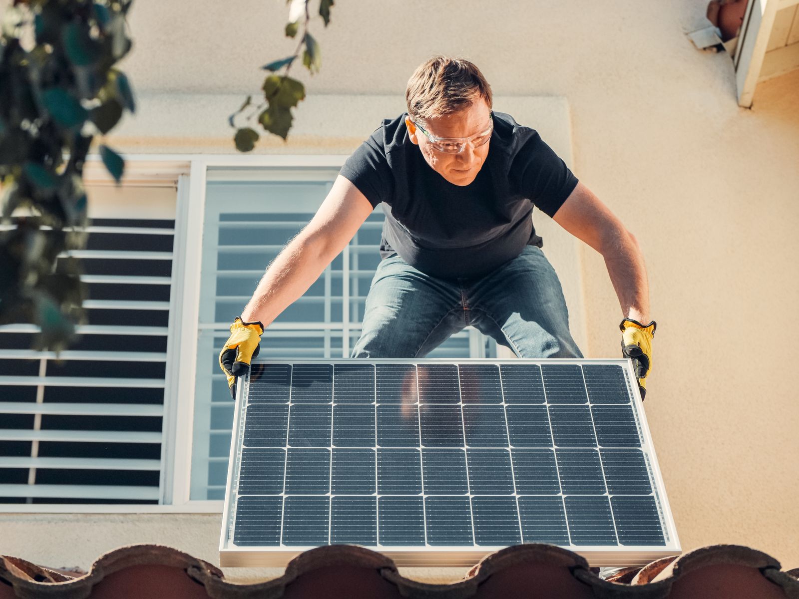 Installateur portant un panneau solaire sur une toiture